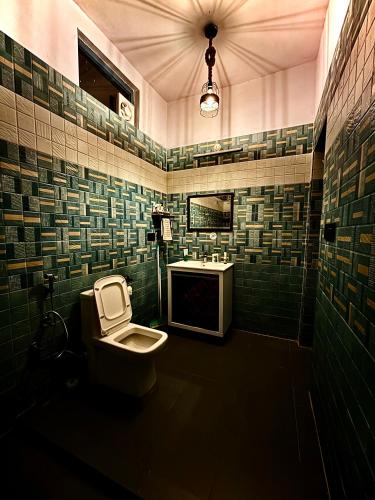a green tiled bathroom with a toilet and a sink at Gaonvasi Homestay in Uttarkāshi