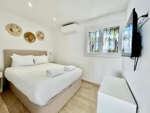 une chambre blanche avec un lit et une télévision dans l'établissement PGH N12 - Thalasso & Plage à 2 pas, Parking Privé, à La Grande Motte