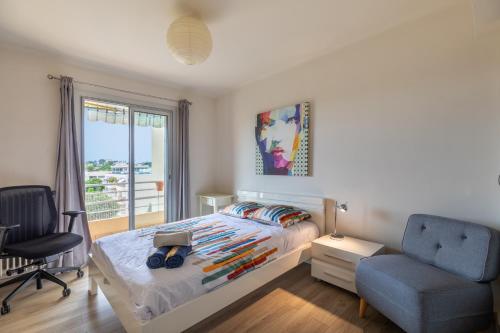 a bedroom with a bed and a chair and a window at Vue mer, 2 pièces Terrasse, 5 min du centre in Antibes