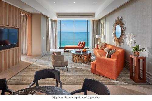 Mandarin Oriental Jumeira, Dubai في دبي: غرفة معيشة مع أثاث برتقالي وإطلالة على المحيط