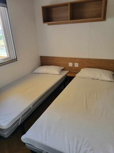 deux lits jumeaux dans une chambre avec fenêtre dans l'établissement Mobilhome au bord de l'eau, à Lège-Cap-Ferret