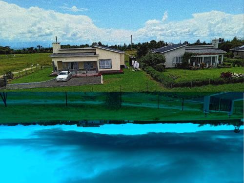 a house with a car parked in front of the water at Enkai Farmhouse near Ol-Pejeta Nanyuki in Nanyuki