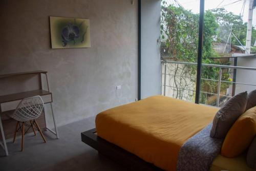 a bedroom with a bed and a desk and a window at Maison Mindo in Mindo