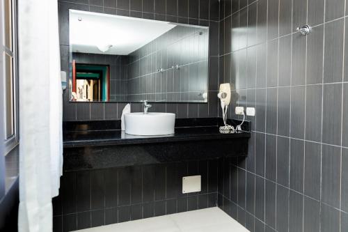 Baño negro con lavabo y espejo en Hotel Brisa en Punta Cana