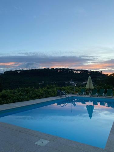 ein Swimmingpool mit einem Sonnenuntergang im Hintergrund in der Unterkunft Casa da Quinta da Mata in Cabeceiras de Basto