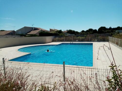 une personne nageant dans une grande piscine dans l'établissement Villa dans résidence jardin piscine parking près de la mer, à Vic-la-Gardiole