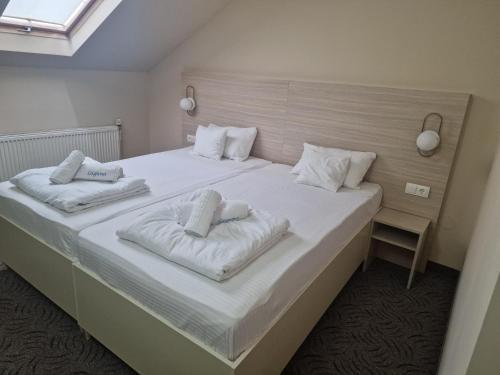 a bedroom with a large white bed with two pillows at Motel LAGUNA in Beiuş