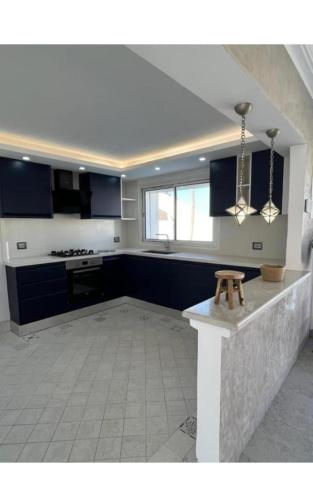 a large kitchen with blue cabinets and a table in it at Dar ayed - proche plage in Mezraya