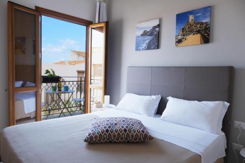 a bedroom with a large white bed and a balcony at Baglio La Riserva in Scopello