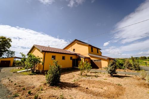 una casa amarilla con árboles delante de ella en Agriturismo Bio Podere 109, en Alberese