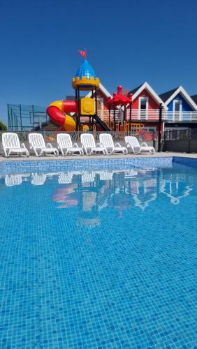 a swimming pool with chairs and a water park at MORZA SZUM basen z podgrzewaną wodą, boisko, rowery in Sarbinowo