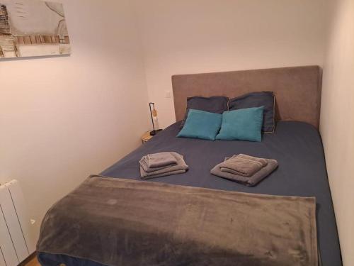 - un lit avec des oreillers bleus et 2 serviettes dans l'établissement Charmant Plain pied, 200m du port, Appart 3, à Binic