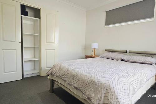 a white bedroom with a bed and a closet at Four Bedroom Modern house in Glen Waverley in Glen Waverley