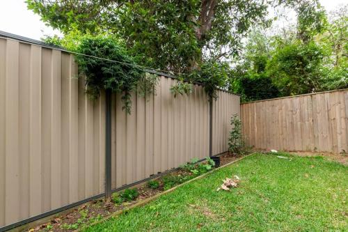 a fence in front of a yard with a green grass at Four Bedroom Modern house in Glen Waverley in Glen Waverley