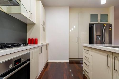 a kitchen with white cabinets and a stove top oven at Four Bedroom Modern house in Glen Waverley in Glen Waverley