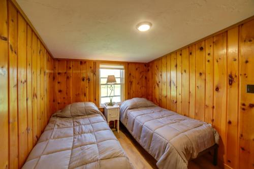 two beds in a room with wooden walls at 600 of Green Bay Frontage and Dock Cozy Cottage in Oconto