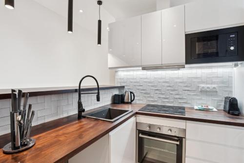 une cuisine blanche avec un évier et une cuisinière dans l'établissement 523 Suite Batignolles - Superbe Appartement, à Paris