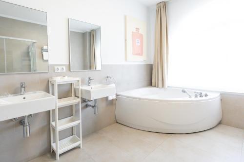 a white bathroom with two sinks and a tub at Apartamentos Regollera Premium con garaje in Noja