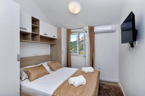 a bedroom with a bed and a tv and a window at Villa Legero mit Pool 300 Meter zum Strand in Drašnice