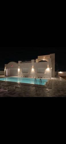 a building with a swimming pool at night at Dar ayed - proche plage in Mezraya