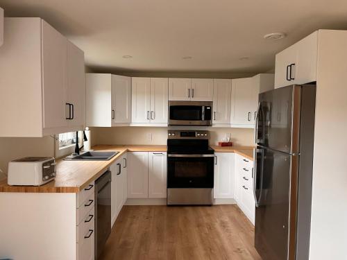 a kitchen with white cabinets and stainless steel appliances at OH Victoria Hotel in Hampton 