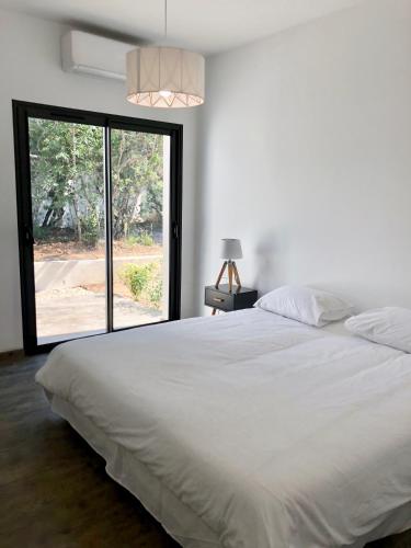 une chambre avec un lit blanc et une grande fenêtre dans l'établissement Villa Porto Vecchio centre, à Porto-Vecchio