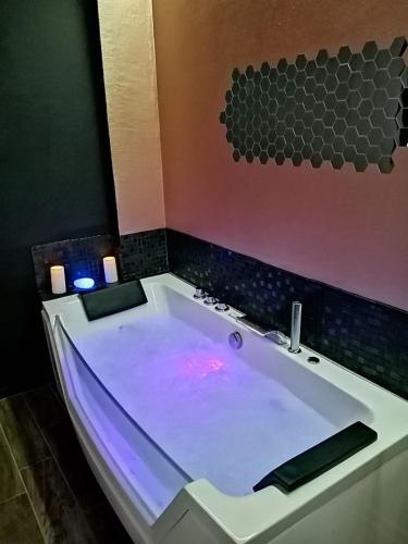 La salle de bains est pourvue d'une grande baignoire avec éclairage violet. dans l'établissement Appartements avec balnéo et sauna privatif - Troyes Centre, à Troyes