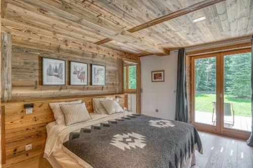 een slaapkamer met een bed en een houten muur bij Chalet River in Megève