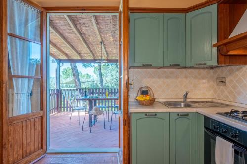 a kitchen with green cabinets and a patio with a table at Villa Sunshine apartments in Gambassi Terme
