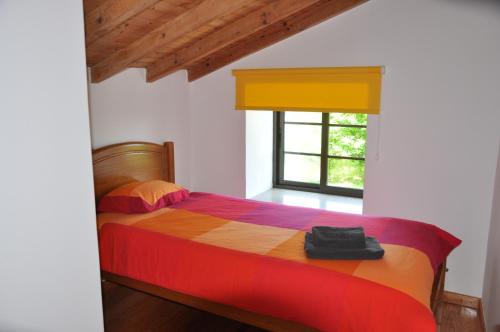 Quinta da Encavalada في Nogueira do Cravo: غرفة نوم مع سرير مع لحاف جميل ونافذة