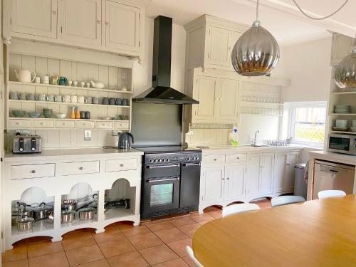 a kitchen with white cabinets and a stove and a table at Close to Snowdon with Mountain views of Snowdonia in Caernarfon