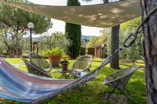 a hammock in a garden with chairs and a table at Villa Sunshine apartments in Gambassi Terme