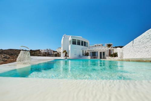 a swimming pool in front of a white house at White Stone Mykonos in Agios Ioannis Mykonos