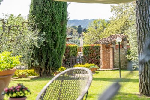 a garden with two white chairs in the grass at Villa Sunshine apartments in Gambassi Terme