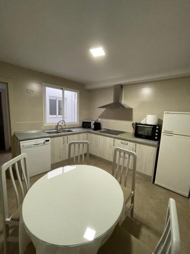 a kitchen with a white table and a white refrigerator at Casa Carmen. Villa Romana Salar in Salar