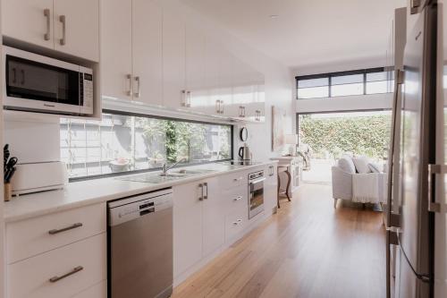霍巴特Stay steps from Salamanca in historical cottage的厨房配有白色橱柜和大窗户