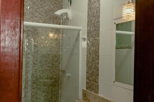 uma casa de banho com uma cabina de duche em vidro e um espelho. em Residencial Diva em Florianópolis