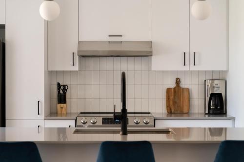 a kitchen with white cabinets and a stove top oven at Maison Rasco by Luxury In Transit in Montréal