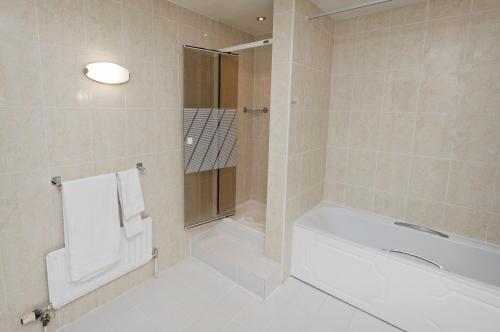 胡克的住宿－貝辛斯托克Spa酒店，白色的浴室设有浴缸和淋浴。