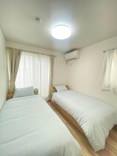 two beds in a room with white sheets at 湘南片瀬HOME in Fujisawa