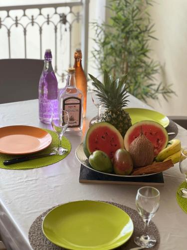 a table with a plate of fruit and bottles of alcohol at Appartement spacieux Les Trois-Îlets 90 m² vue sur mer in Les Trois-Îlets
