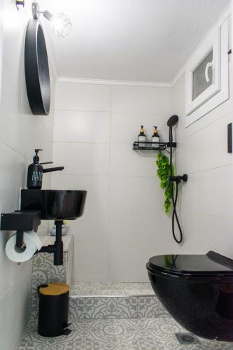 a bathroom with a black toilet and a sink at VespaHome in Kavála