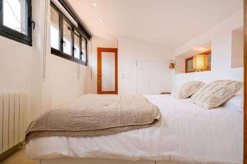 una camera bianca con un grande letto bianco con cuscini di Ca lEudald 3 Apartamento en Besalú con terraza a Besalú