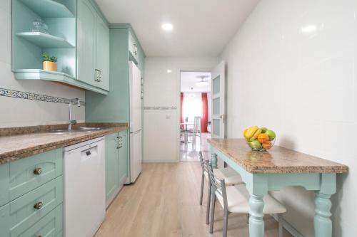 a kitchen with blue cabinets and a table with fruit on it at Los Áticos in Estepona