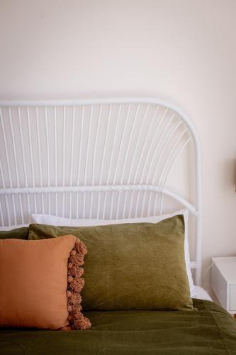 a bed with a white headboard and some pillows at 'Lazy Susan's' Waterfront Shack in Primrose Sands