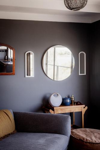 a living room with a couch and two circular mirrors at 'Lazy Susan's' Waterfront Shack in Primrose Sands
