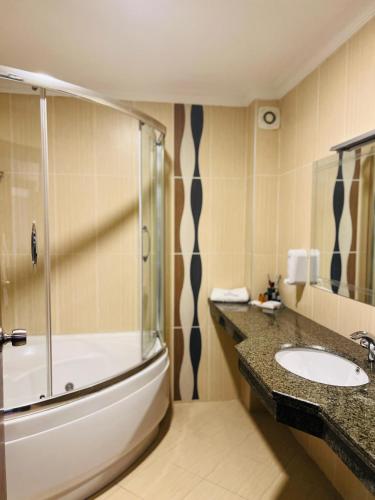 a bathroom with a shower and a sink and a tub at BM HOTEL City in Samsun