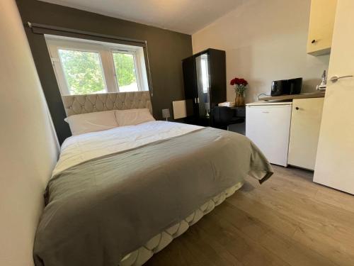 a bedroom with a large bed and a kitchen at Letzi Private En-Suite Near Wembley in London