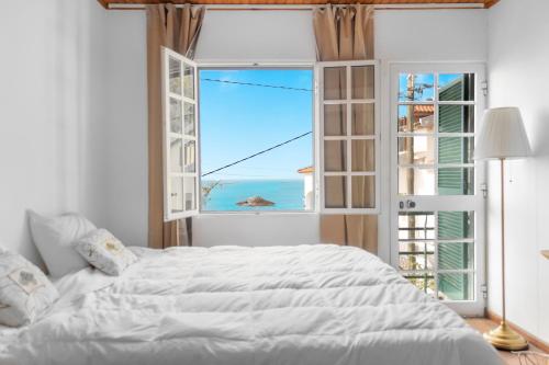 Un dormitorio con una gran cama blanca y una ventana. en Cecília's House, en Jardim do Mar