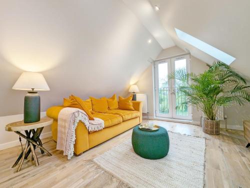 a living room with a yellow couch and a large window at Roseland Penthouse - Arundel in Arundel